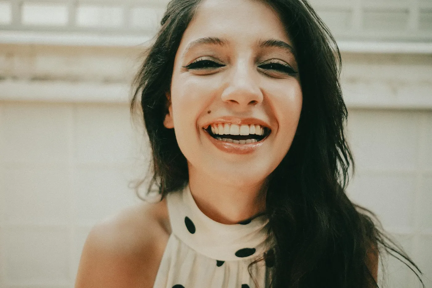 Young woman with a joyful expression and bright smile indoors. Close-up portrait.