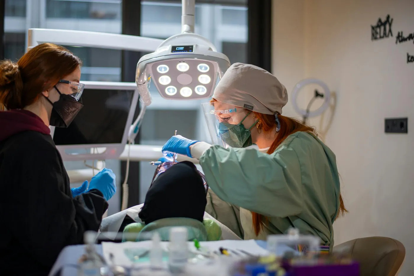 Dentist performing dental procedure with assistant in modern clinic setting.